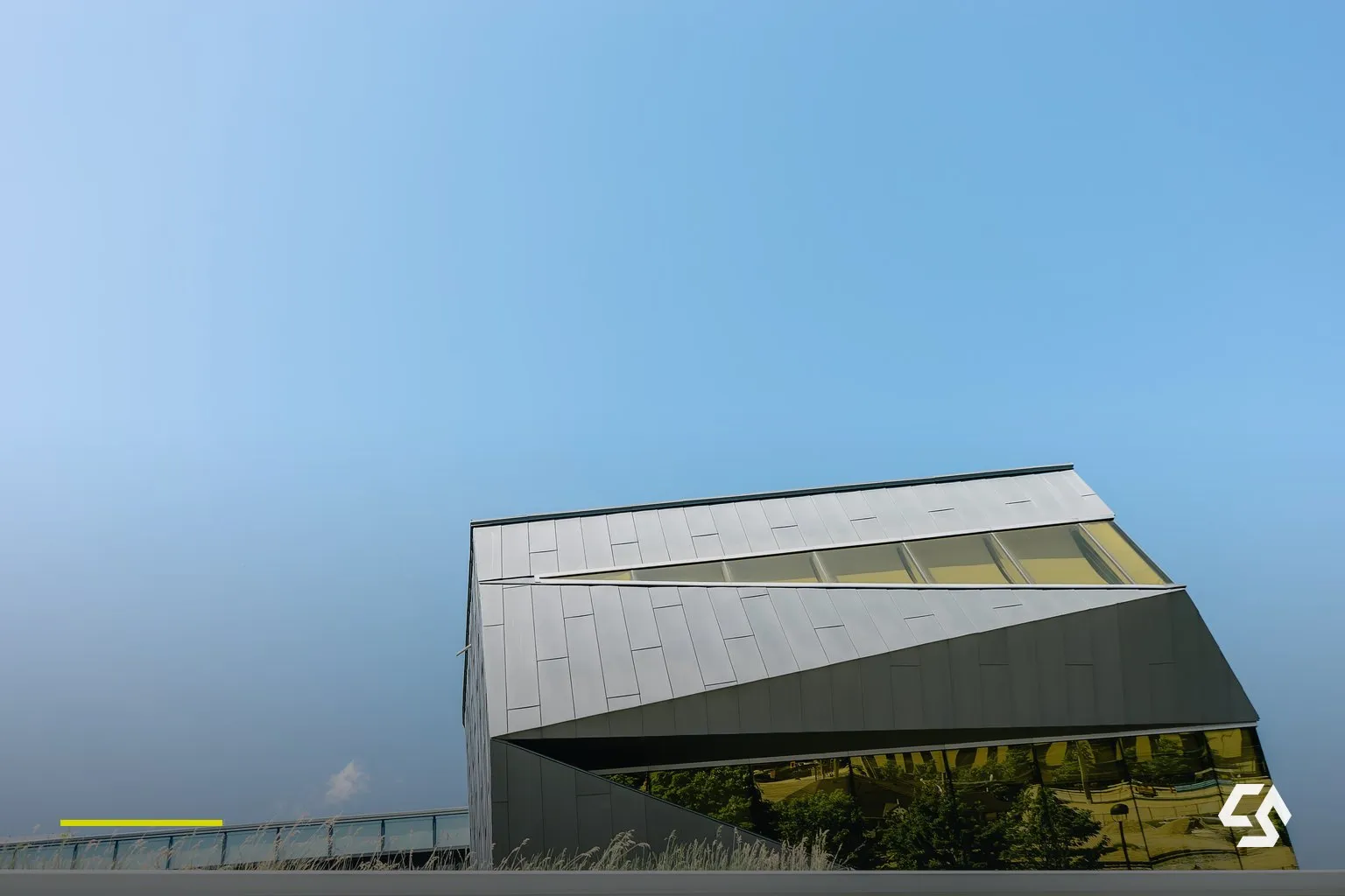 Klare Glas- und Metallfassade eines modernen Gebäudes vor hellem Himmel.