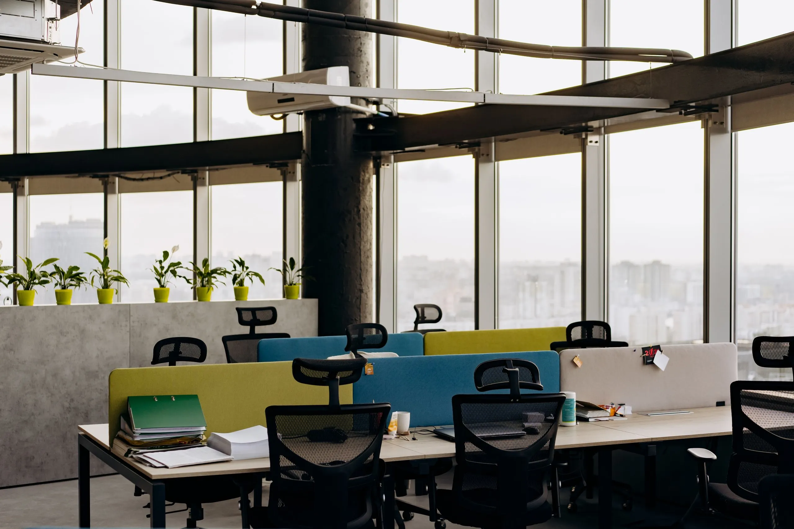 Ein offenes, modernes Büro mit großen Fenstern, Pflanzen und Blick über die Stadt.